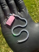 Solid 14K white gold tennis bracelet with 4.45 CTW lab-grown diamonds coiled on a gloved hand with a pink tag