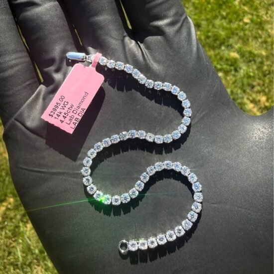 Solid 14K white gold tennis bracelet with 4.45 CTW lab-grown diamonds coiled on a gloved hand with a pink tag