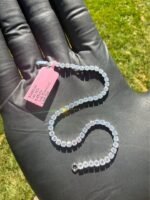Solid 14K white gold tennis bracelet with 4.45 CTW lab-grown diamonds on a gloved hand with a pink tag, close view