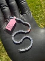 Solid 14K white gold tennis bracelet with 4.45 CTW lab-grown diamonds on a gloved hand with a pink tag, angled view