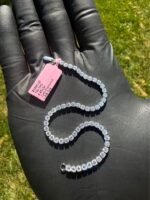 Solid 14K white gold tennis bracelet with 4.45 CTW lab-grown diamonds on a gloved hand with a pink tag, detail view